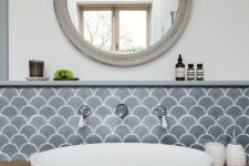 a catchy space with grey fishscale tiles, a stained vanity, a round sink, a mirror in a shabby chic frame, wall sconces