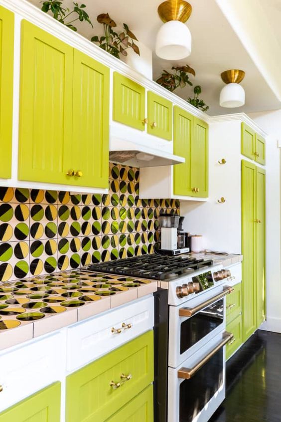 a chartreuse and white kitchen with a whimsical printed tile backsplash and countertops plus brass touches