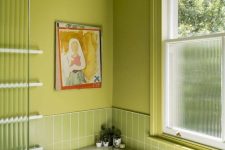 a chartreuse bathroom with stacked skinny tiles, a window covered for privacy and some art is extra bold and wow
