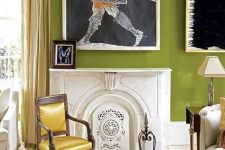 a chartreuse living room with a fireplace, a refined sofa, chair and ottoman, some statement art and a crystal chandelier