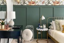 a chic bedroom with green wall paneling and botanical wallpaper, a forged bed and a nightstand, a black vanity and a clear chair