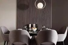 a chic contemporary taupe dining room with a dark wooden slats on the wall, a black table, grey chairs and catchy pendant lamps