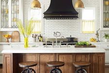 a chic vintage kitchen in white, with a stained kitchen island, a white tile backsplash and a bold black hood over the cooker