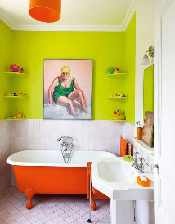 a colorful bathroom with chartreuse walls, white tiles, a red clawfoot bathtub, some decor and an orange pendant lamp