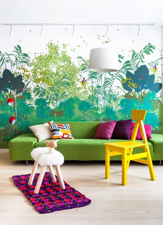 a colorful living room with a bold floral wall mural, a chartreuse sectional, a bold rug and some stools is awesome
