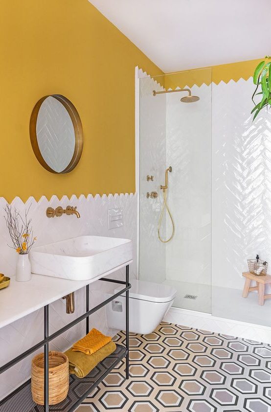 A colorful mid century modern bathroom with mustard walls, a mosaic tile floor, a white tile shower space and mustard towels