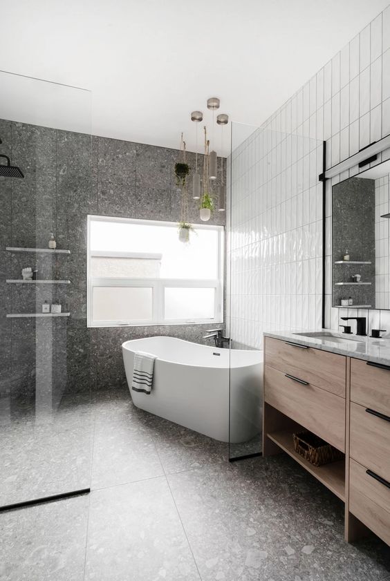 a contemporary bathroom clad with grey terrazzo and white stacked tiles, a shower space and a vanity