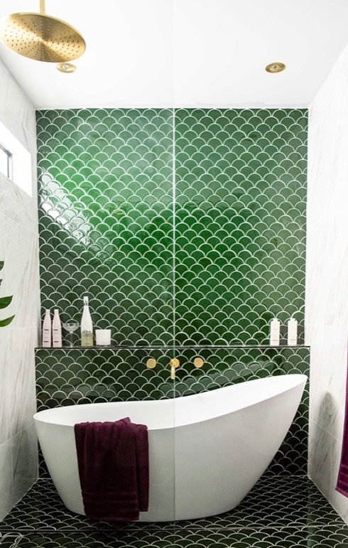 a cool bathroom with white marble and green fishscale tiles, a tub in the shower space and gold fixtures is chic and cool