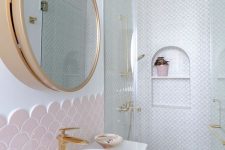 a cute bathroom done with blush fihscale and neutral printed tiles, a sink, a mirror cabinet in a gold frame is chic and cool