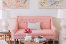 a feminine living room with a peachy pink loveseat and grey chairs, a neutral ottoman, a floral rug and pastel watercolors is amazing