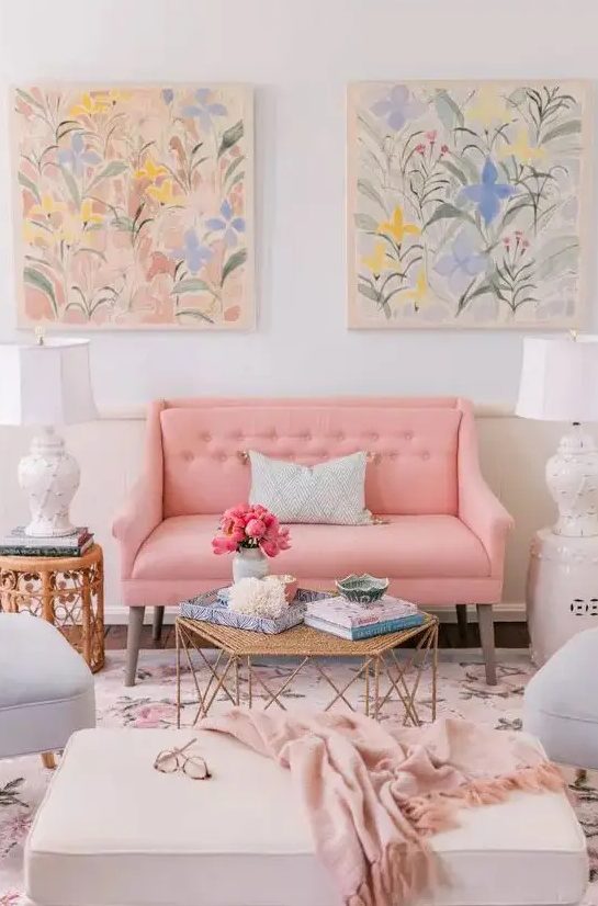 a feminine living room with a peachy pink loveseat and grey chairs, a neutral ottoman, a floral rug and pastel watercolors is amazing