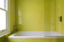 a fully chartreuse bathroom with square tiles and a glass wall is a cool idea if you love bold colors