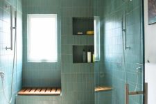 a large shower space clad with green stacked tiles, with niche shelves and a seat is a cool and stylish idea