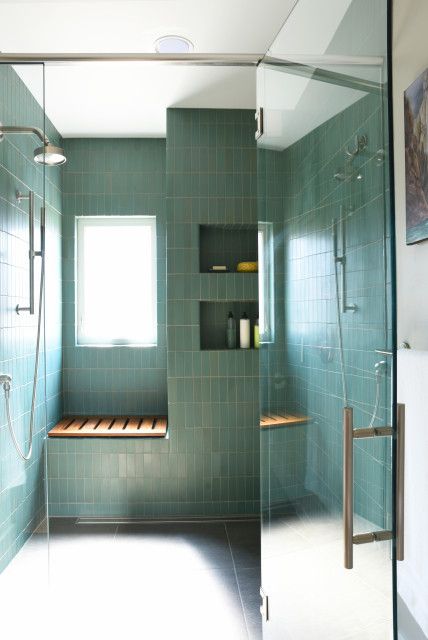 a large shower space clad with green stacked tiles, with niche shelves and a seat is a cool and stylish idea