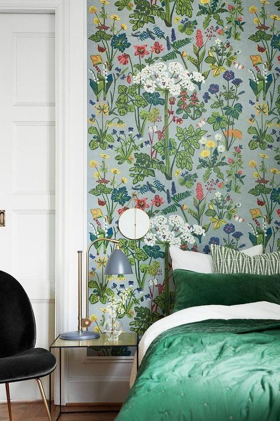 a lively and bold bedroom accented with bright floral wallpaper and with green bedding that matches the wallpaper