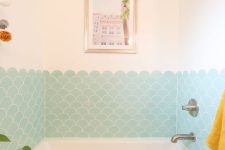 a lovely bathroom done with aqua scallop tiles, with a small bathtub and some decor and a potted plant is great