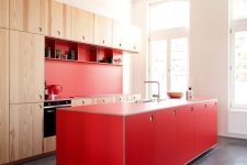 a lovely light-stained and red kitchen with a bold kitchen island and open shelves is a catchy and bold space