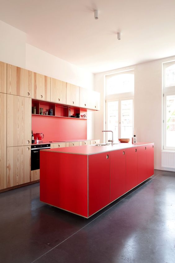 A lovely light stained and red kitchen with a bold kitchen island and open shelves is a catchy and bold space