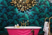 a maximalist bathroom with a tropical leaf wall, a black and white geometric floor, a hot pink tub and gold touches