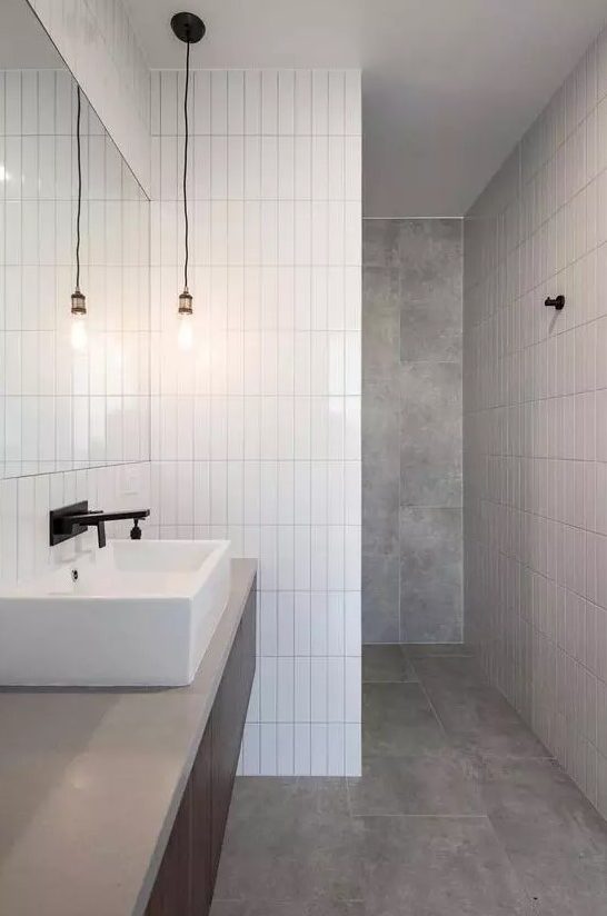 A minimalist bathroom done with grey tiles and white skinny stacked ones for an eye catchy touch