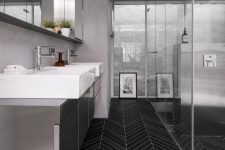 a minimalist bathroom with grey walls and a grey vnaity plus a catchy black skinny tile floor for a contrast
