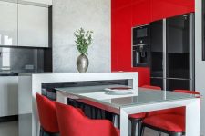 a minimalist red and white glossy kitchen with a sculptural kitchen island and a table, red chairs and a creative chandelier