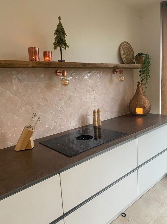 a minimalist white kitchen with sleek cabinets, an open shelf, a blush scallop tile backsplash and dark stone countertops