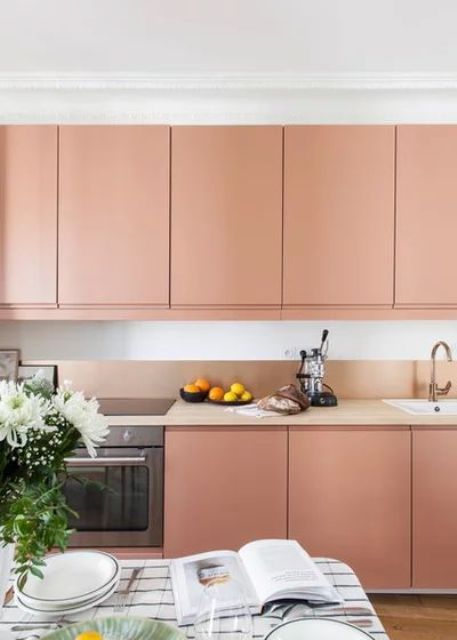 a modern Peach Fuzz kitchen with no handles, a small peachy backsplash and tan countertops, a table right here