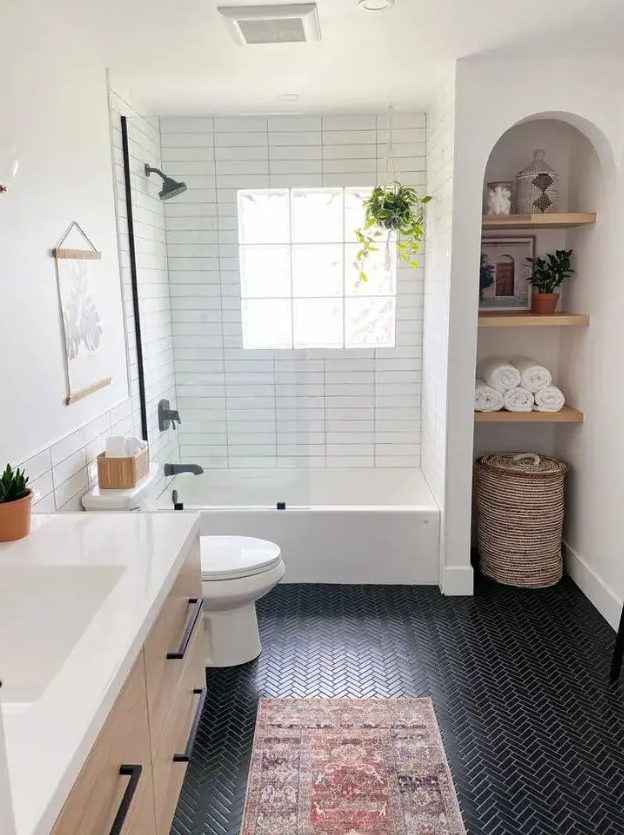 A modern farmhouse bathroom with an arched niche and built in shelves, black herringbone and white skinny tiles, a timber vanity and some decor
