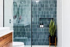 a modern farmhouse bathroom with blue stacked tiles and merble hex ones, a stained vanity, a statement plant in the shower