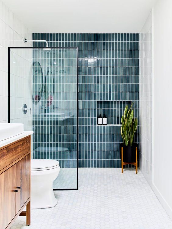 a modern farmhouse bathroom with blue stacked tiles and merble hex ones, a stained vanity, a statement plant in the shower