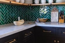 a modern farmhouse kitchen with navy cabinets, a white stone countertop, an emerald herringbone tile backsplash, open shelves, potted plants