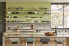 a modern kitchen with a chartreuse wall with shelves, a stone backsplash and countertops, a fluted kitchen island