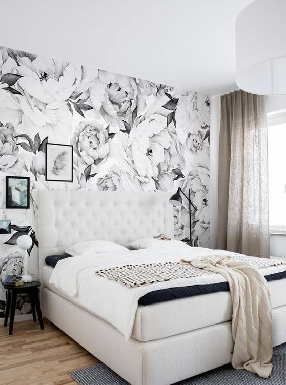 a monochromatic bedroom with a floral print wall that adds a bold print touch to the space