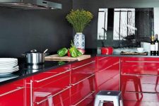 a moody kitchen with black walls and glossy red lower cabinets for a contrast, metallic stools and a glass backsplash