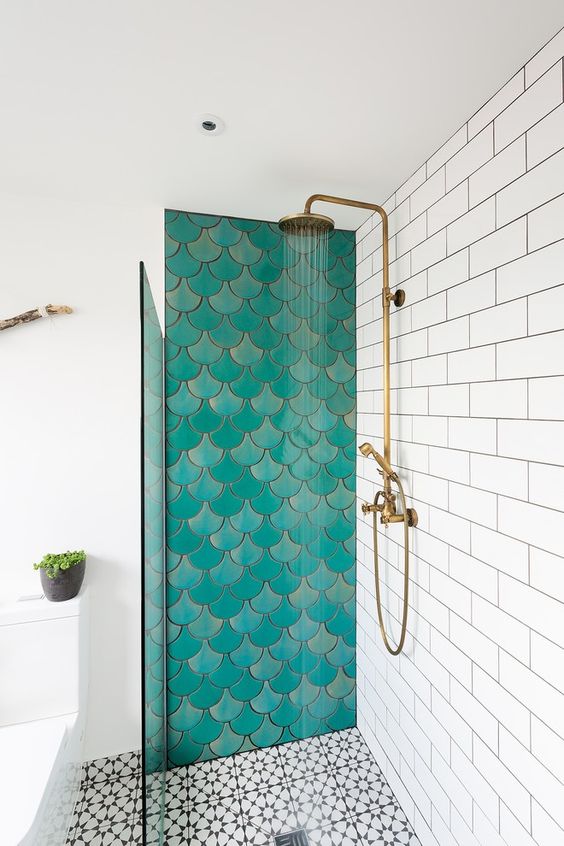 a neutral bathroom with a shower space that features an accent wall done with turquoise scallop tiles and brass fixtures