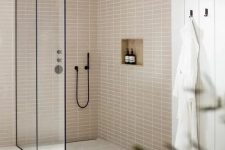 a neutral bathroom with planked walls and tan stacked tiles, a large shower space, black details for a contrast