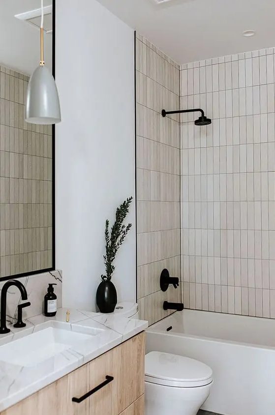 a neutral bathroom with white walls, tan skinny stacked tiles, a stained vanity, black details for some drama