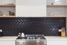a neutral kitchen with a black herringbone tile backsplash, a hood and open shelves looks bold and contrasting