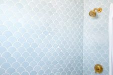 a pale blue bathroom clad with fishscale tiles and accented with gold looks refined and stylish
