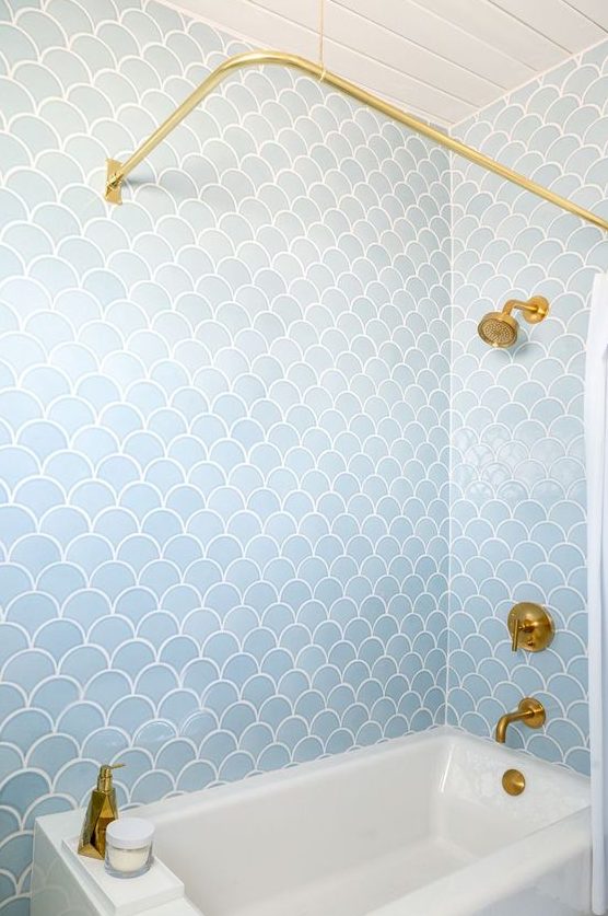 a pale blue bathroom clad with fishscale tiles and accented with gold looks refined and stylish