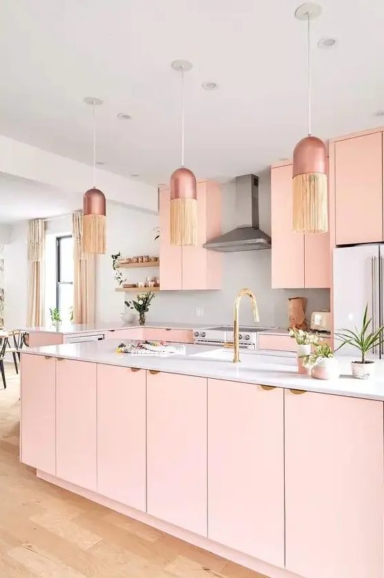 a peachy pink kitchen with plain cabinets, a large kitchen island, a white backsplash and coutnertops, pendant lamps with fringe