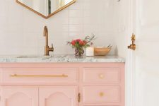 a peachy pink sink console with a marble top and gold handles and knobs are ideal for a glam bathroom look
