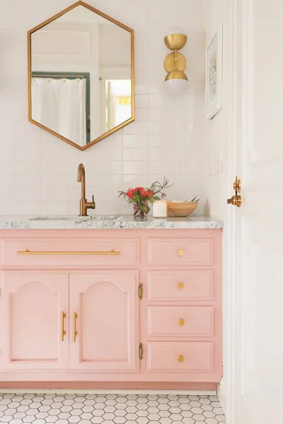 a peachy pink sink console with a marble top and gold handles and knobs are ideal for a glam bathroom look