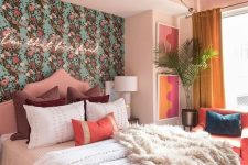 a pretty bedroom with a floral wallpaper wall, a neon sign, a pink canopy on the ceiling, a coral chair and bright artworks