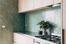 a sleek contemporary kitchen with MDF cabinets, a green herringbone tile backsplash, a bold boho rug