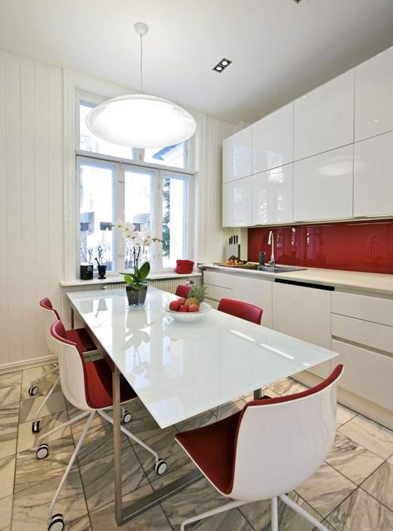 a sleek white kitchen with plain cabinets and a sleek red backsplash plus red chairs is a bold idea for a minimalism fan