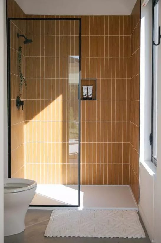 a small contemporary bathroom with stacked yellow skinny tiles in the shower, white appliances and a window for natural light