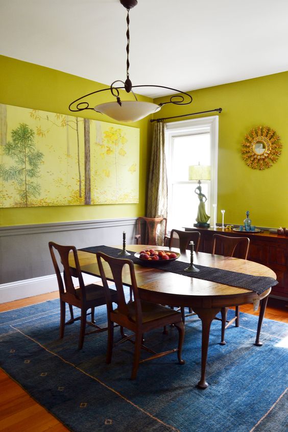 a sophisticated chartreuse dining room with paneling, a vintage dinign furniture set, a console table and some artwork