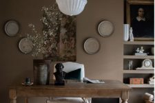 a sophisticated taupe home office with open shelves, a vintage desk, a white chair, some decor and a pendant lamp